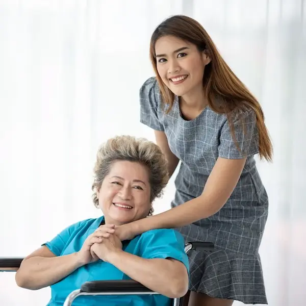 Smiling young occupational therapist leaning lovingly over a elderly asian paitent