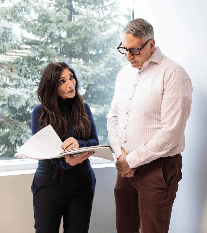 Two SteriMax team members reviewing documents together in an office by a window.