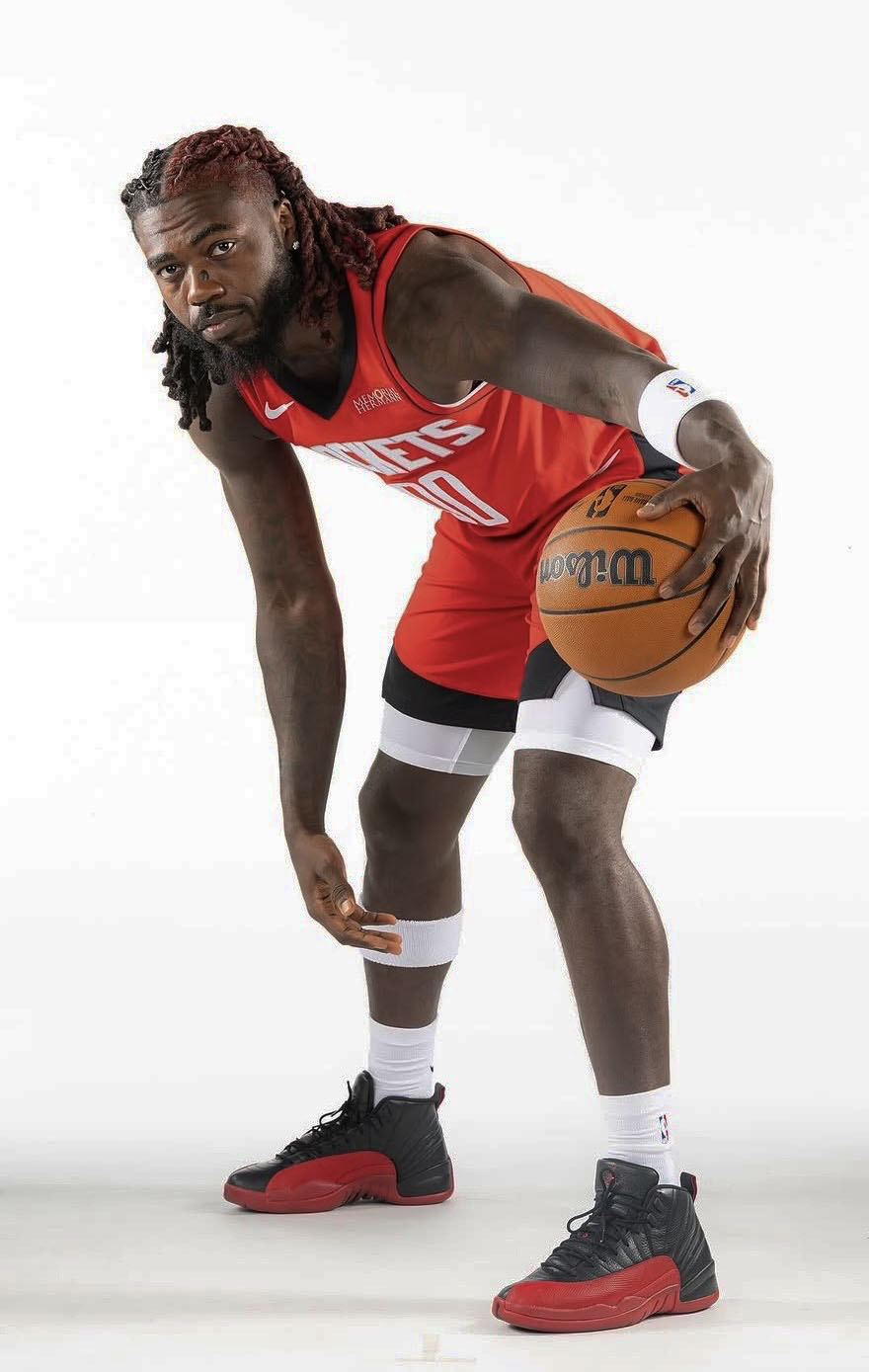 Kevon Harris in a red Houston Rockets uniform dribbles a basketball with his right hand, bending forward slightly, against a plain white background.