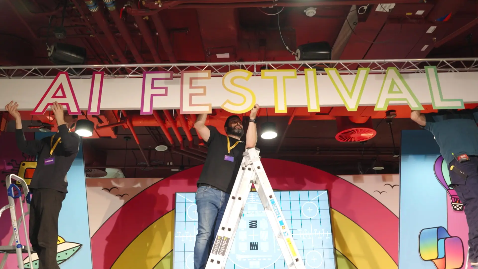 Production crew installing large “AI Festival” signage above the main stage during event build.