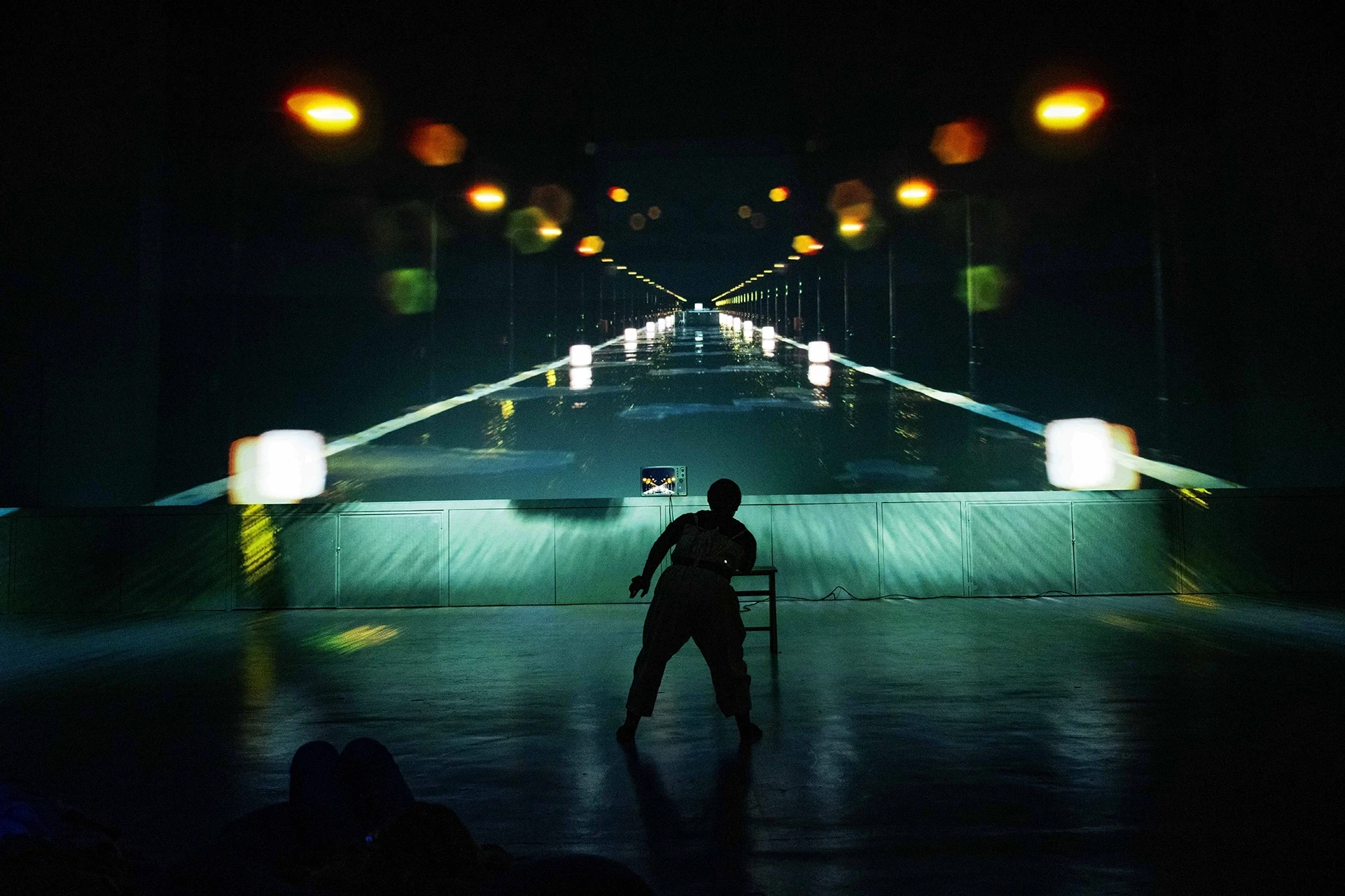 Silhouette of person performing in front of projected road scene.