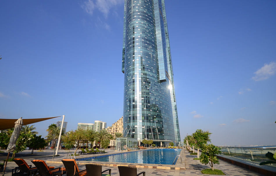 High-rise building with an outdoor swimming pool, featuring luxury lifestyle properties for real estate investors.