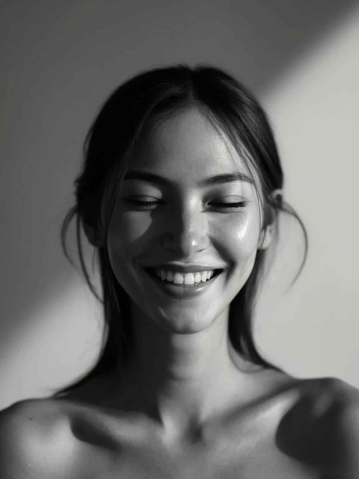 Weibliches KI-Model in emotionalem Schwarz-Weiß-Porträt, das mit geschlossenen Augen und natürlichem Lächeln weiche Lichtakzente und pure Beauty-Ästhetik ausstrahlt.
