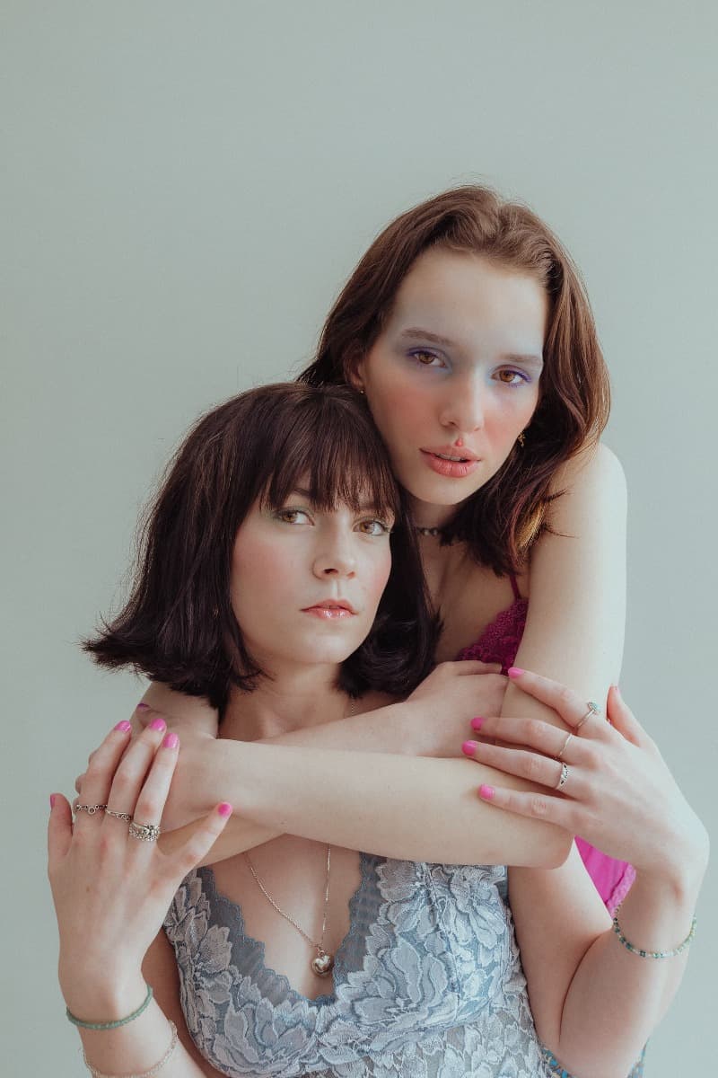 A model in a pink top embraces another in a blue lace top during a creative photoshoot at Revelator Studio, a natural light studio in Shreveport.