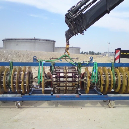 Kran hebt ein Pipeline-Inspektionswerkzeug mit mehreren Scheiben und einem Metallrahmen, bereit für die Wartung.