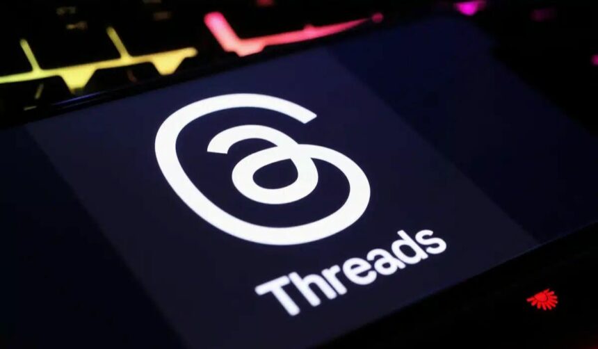 Threads logo displayed on a dark screen with stylized red, yellow, and pink wave patterns in the background.