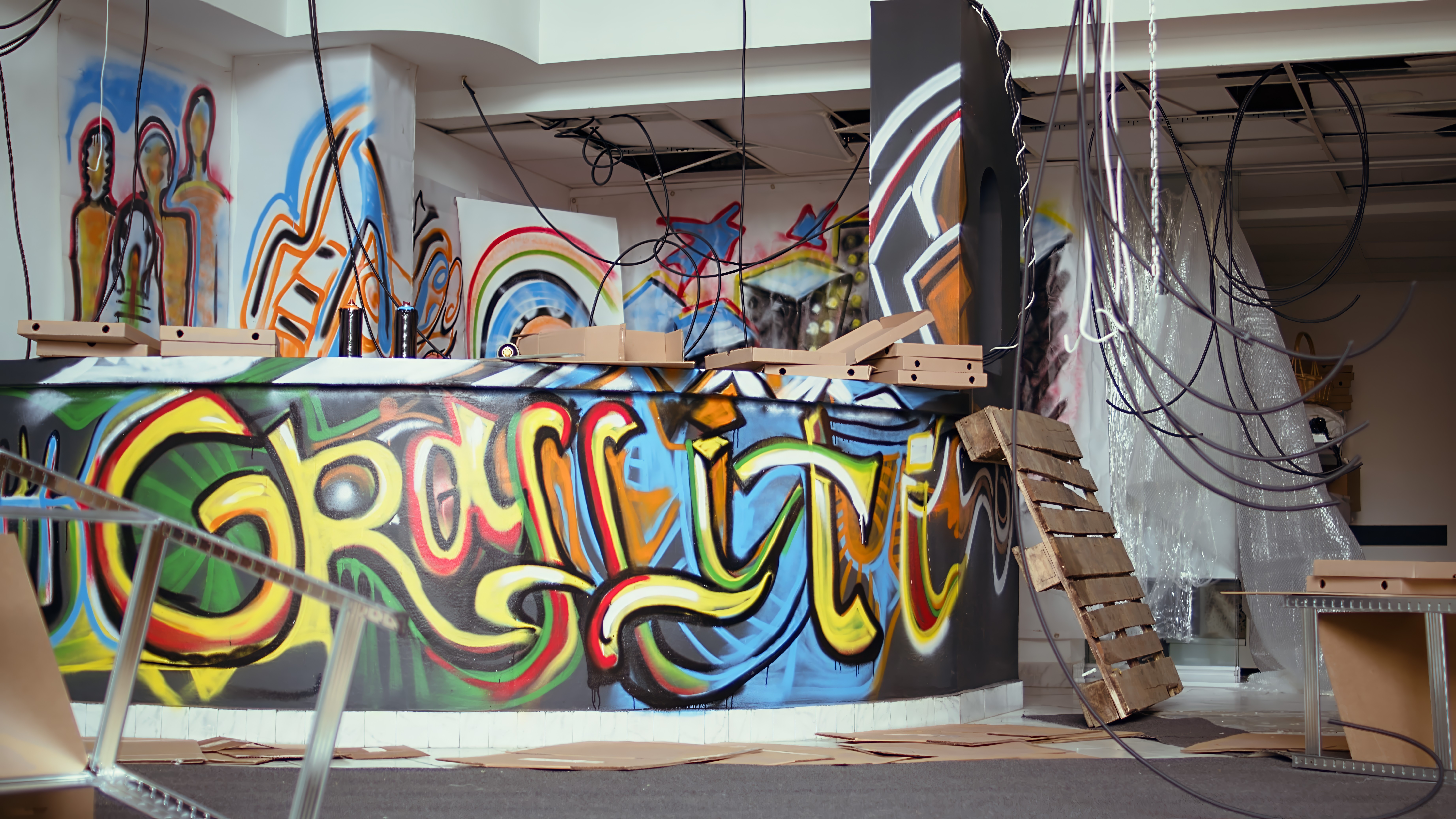 A smiling woman with her arms crossed, standing against a dark green background. She has long, dark hair.