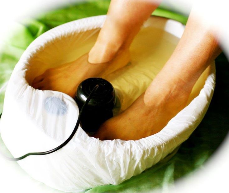 A woman lying down with a towel wrapped around her head, her face glowing with facial oil. She has a peaceful expression, enjoying a skincare treatment.
