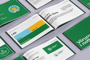 A sleek phone, likely an iPhone 16 Pro, is displayed at an angle between dark rock formations. The screen shows a futuristic design and download promo