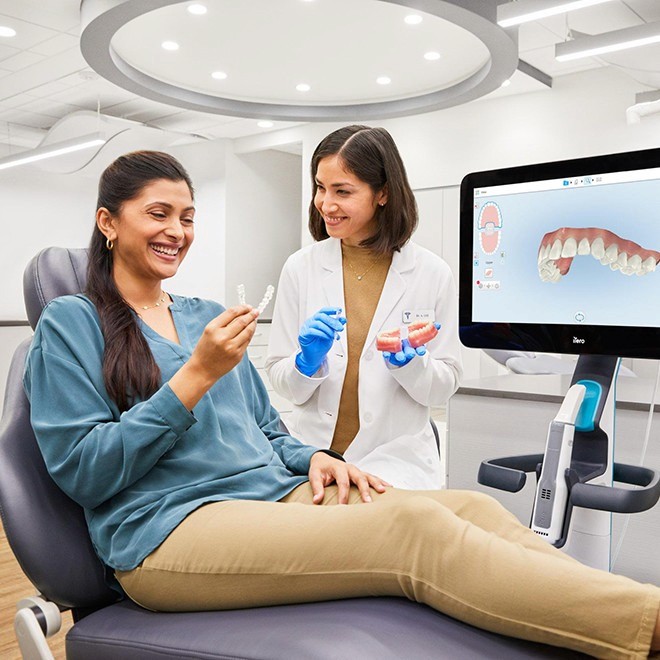 Invisalign in Dubai is guiding a patient as she tries her new aligners during a follow-up appointment at a modern dental clinic.