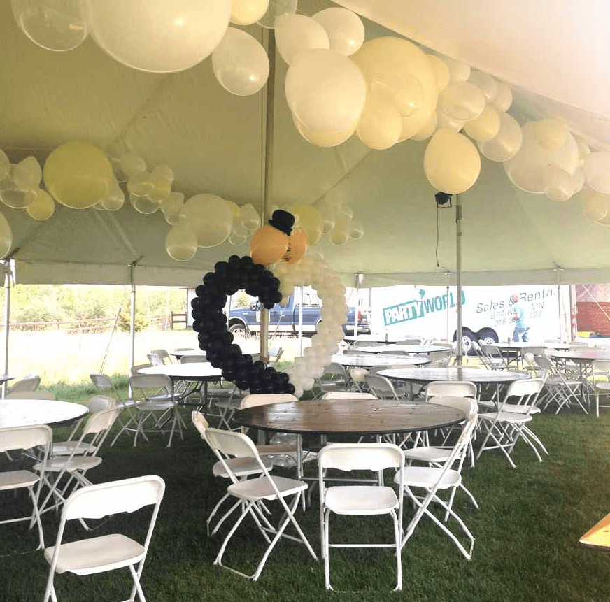 Balloon ceiling installation with white balloons and hanging decorations above tables at an outdoor event by Be Bold Balloons