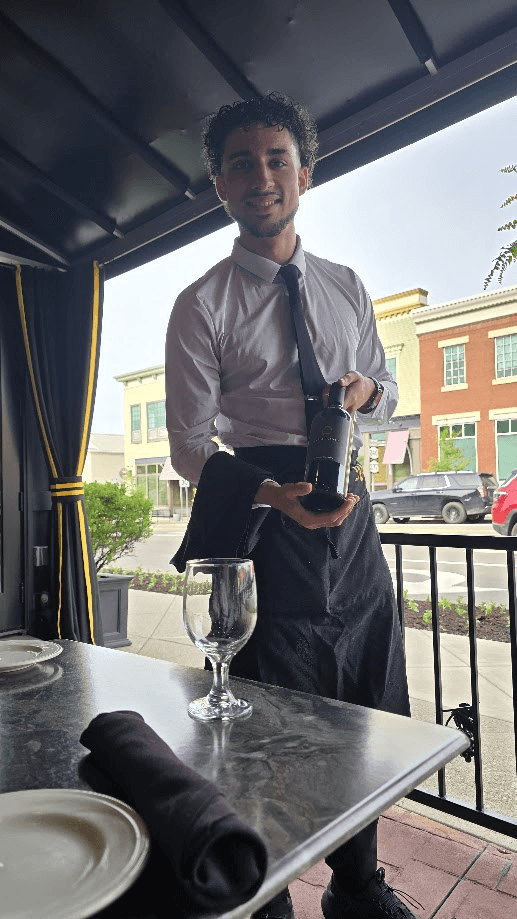 Frank presenting a bottle of wine at a restaurant table