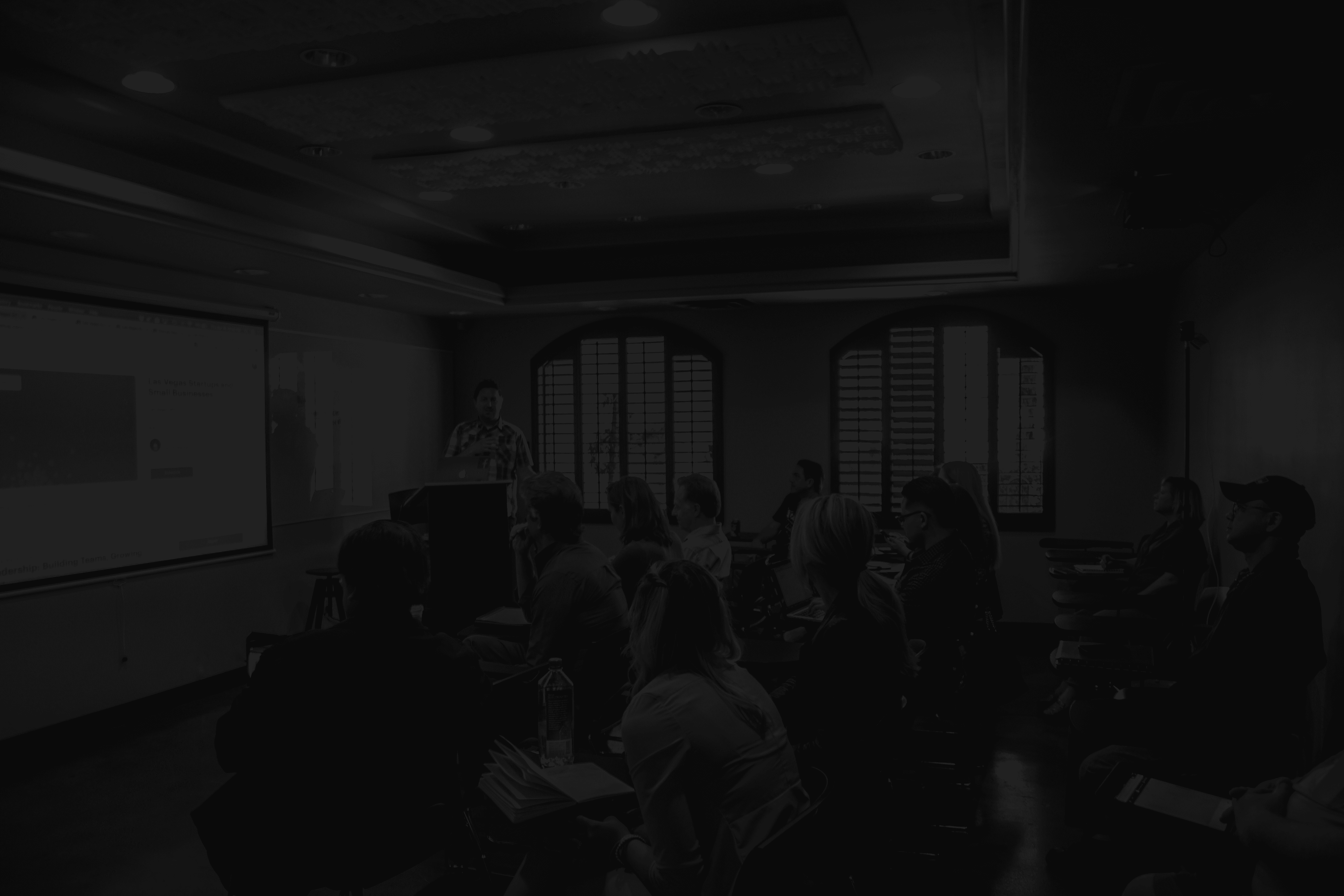 a group of people in a room with a projector screen