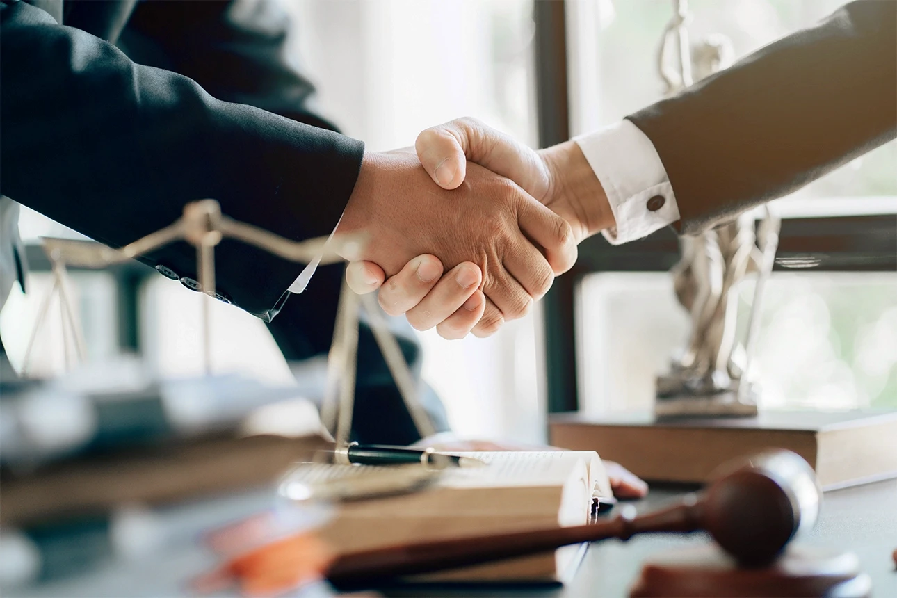 Attorney-client handshake over a legal desk symbolizing trust, case results, and client satisfaction