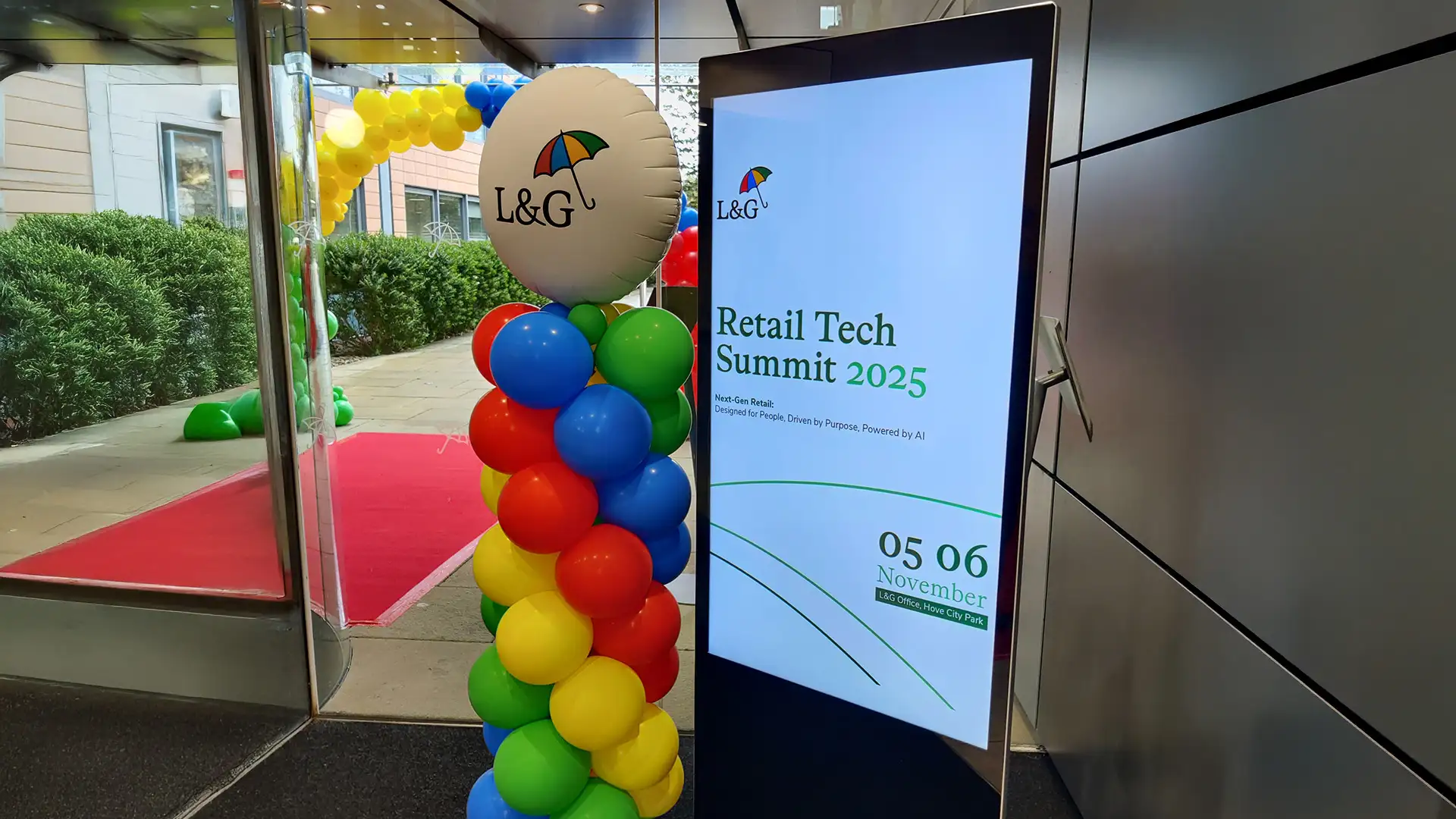 L&G Retail Tech Summit entrance featuring red carpet, branded digital signage and balloon installation.