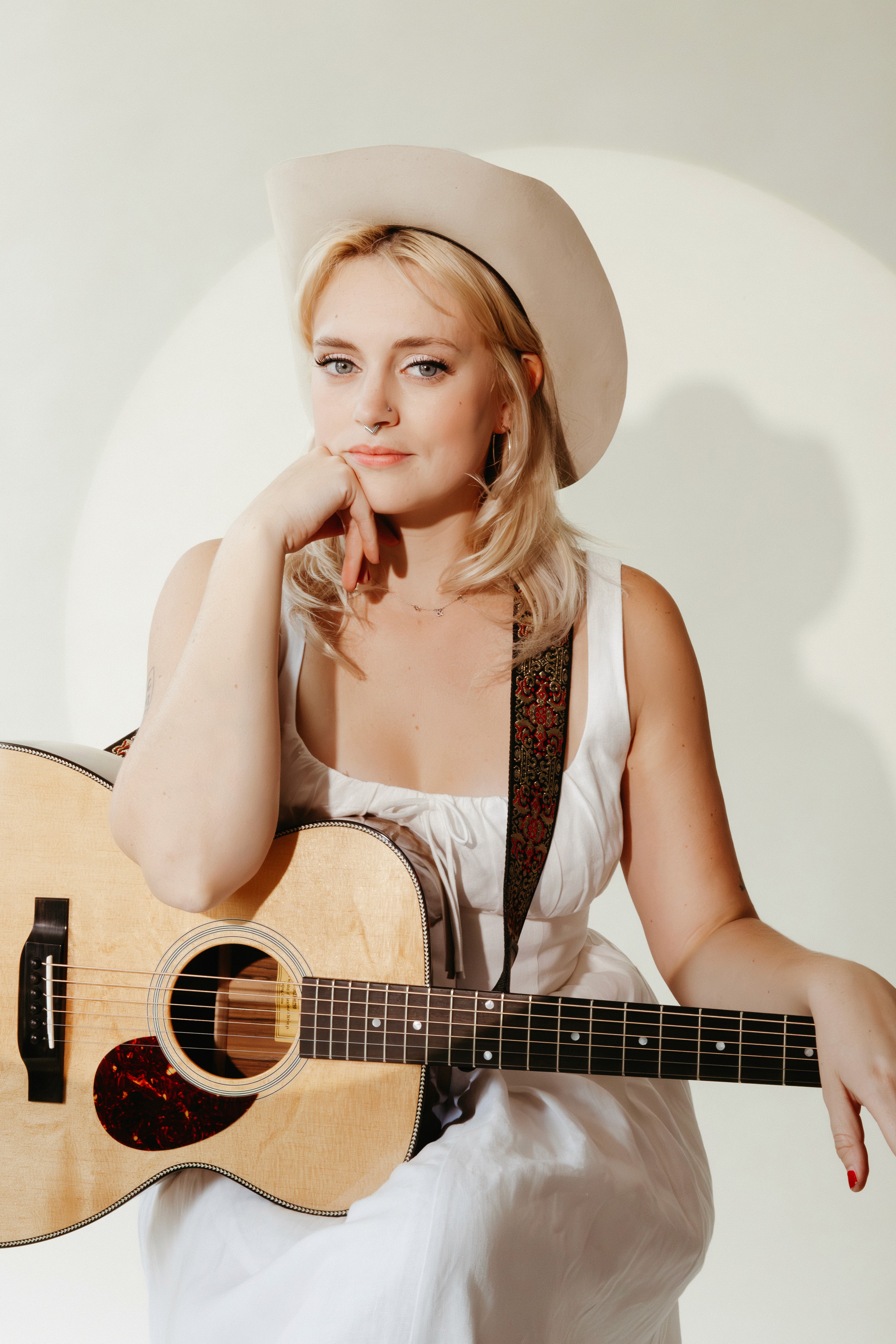 Headshot of Guinevere Goodwin with her guitar in a spotlight on a white background