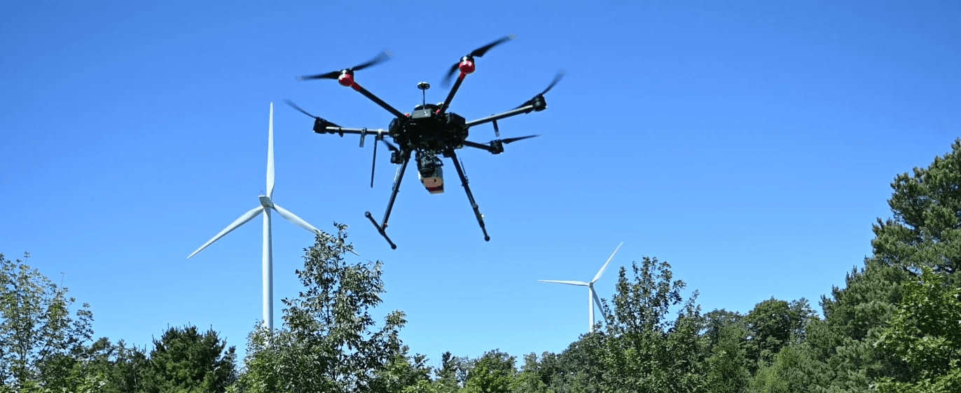 A winding road cuts through rocky terrain, surrounded by patches of green grass and illuminated by sunlight.