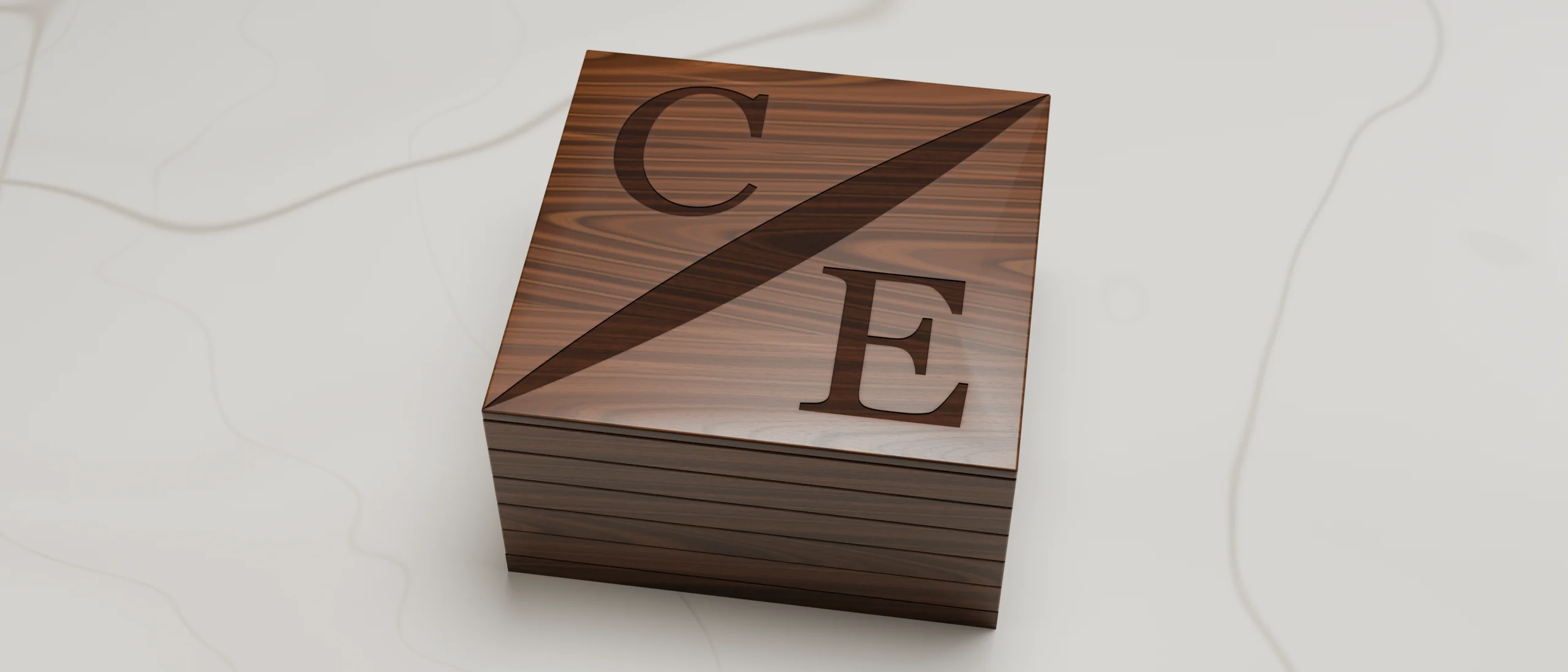 The closed walnut case on white Calacatta marble: the C/E mark carved and burned into the lid and its seven layers stacked along the side