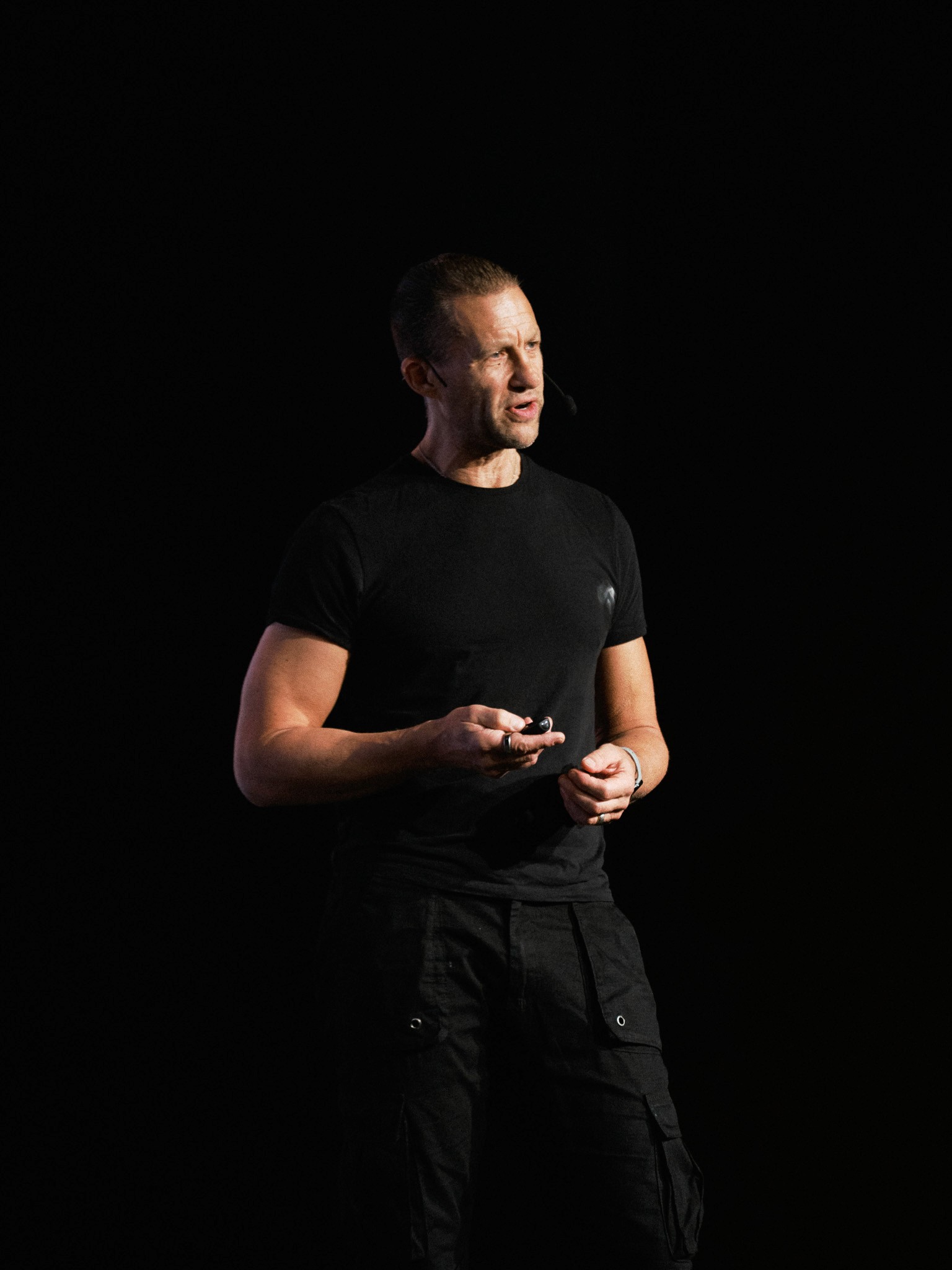 Talare i svart t-shirt med headset på scenen mot mörk bakgrund