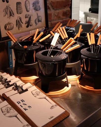 Multiple fondue pots with skewers arranged on a counter, with menus placed in front.
