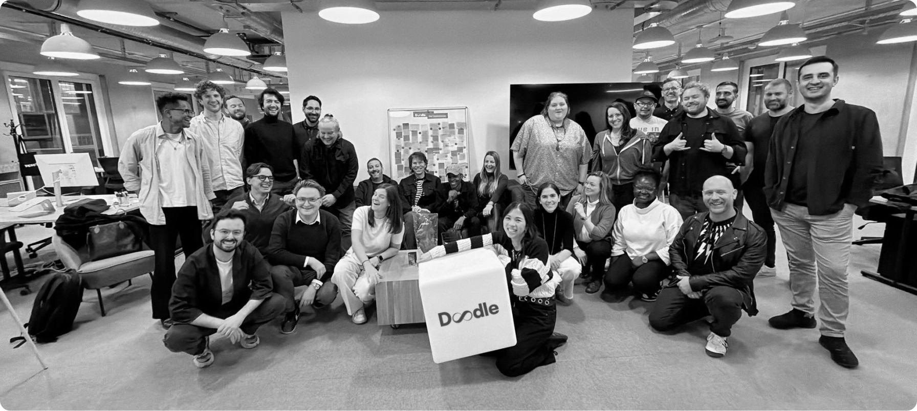 The diverse Doodle company team posing in their modern office, showcasing the experts behind the time management for business solutions and enterprise scheduling software.