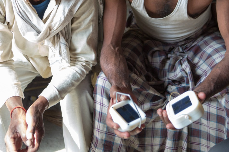 Man holding two prototypes of solar portable light prototypes.