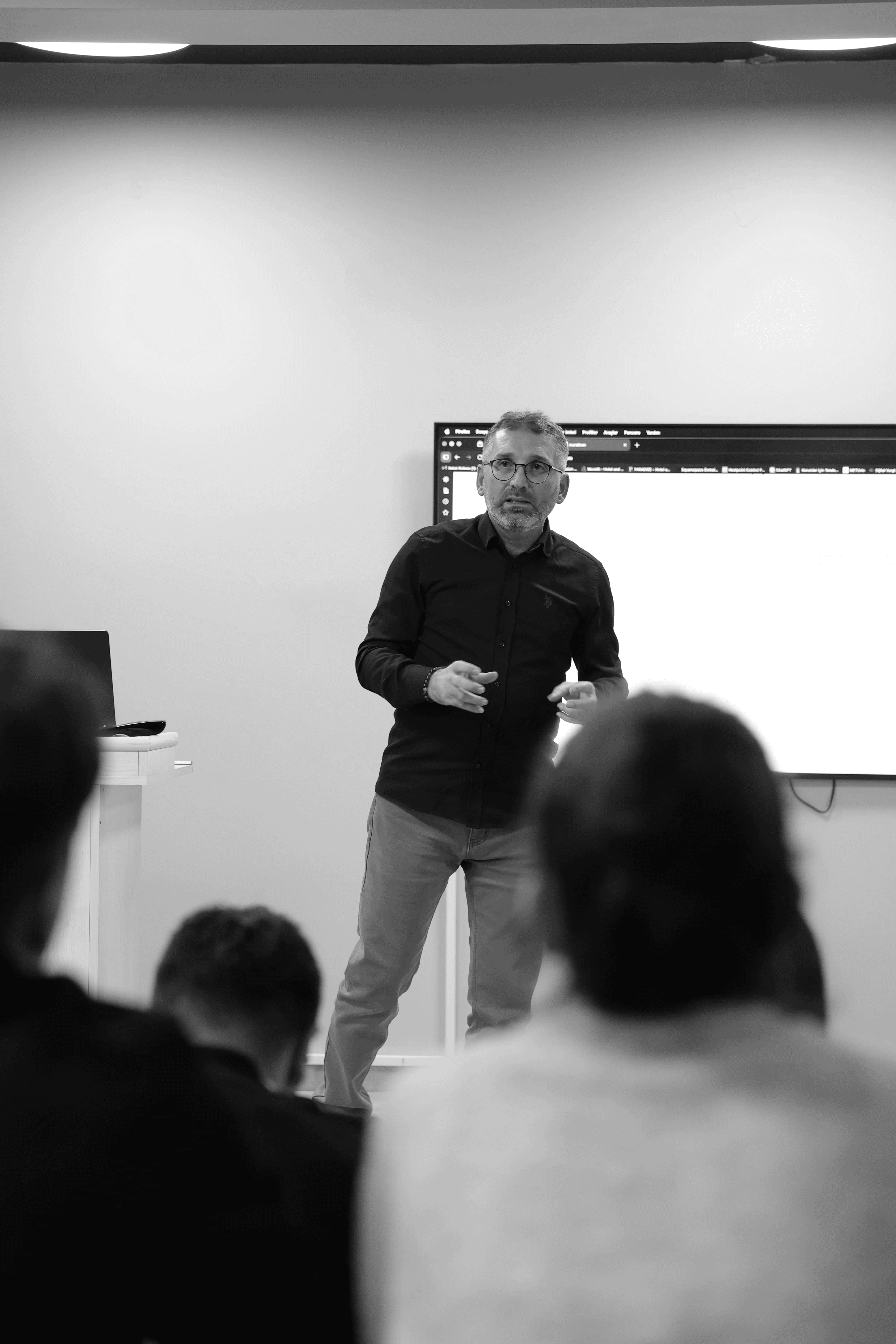Four people engage in conversation in front of a wall with text, all smiling and interacting in a casual setting.