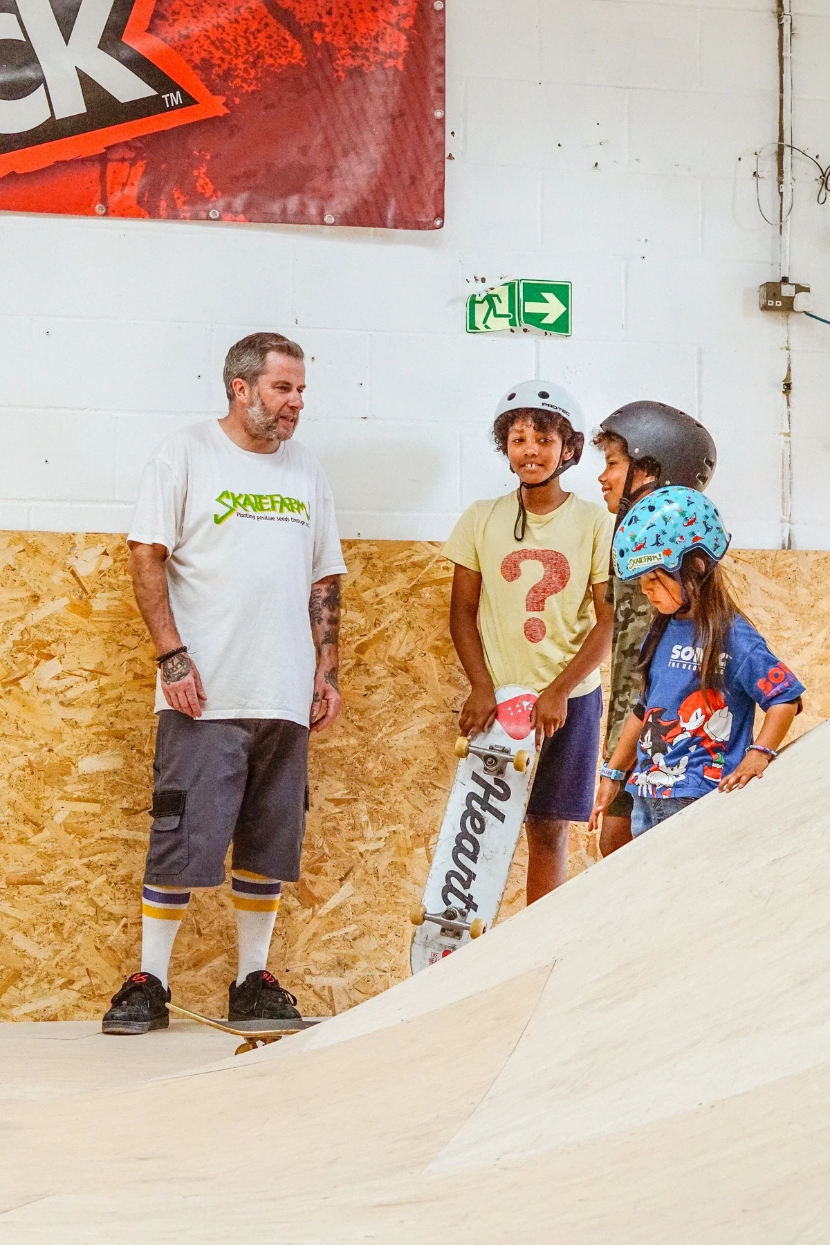 A skate coach talking with two young riders at The Skate Farm indoor skatepark in Sussex