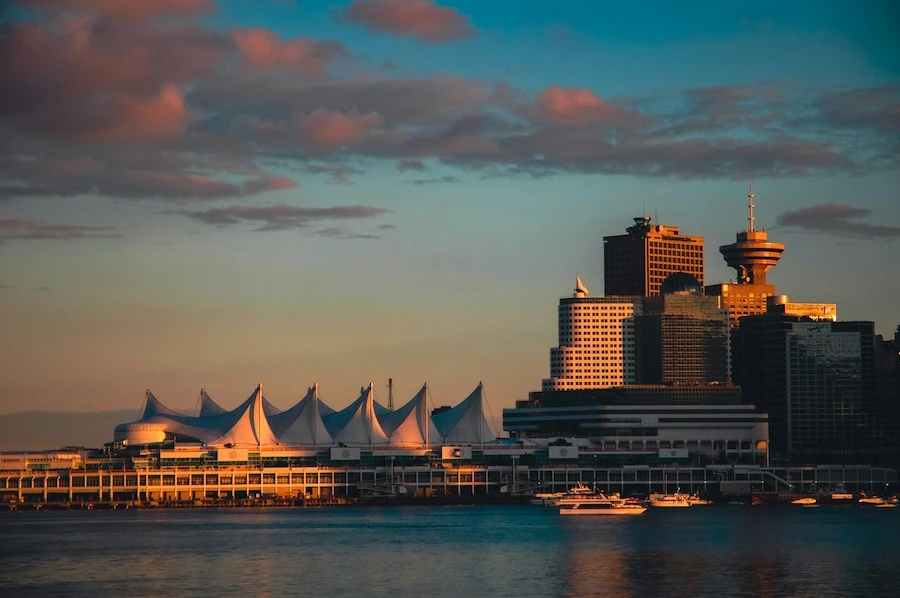 Coal Harbour at golden hour featuring Canada Place sails, waterfront high-rises, and boats on the water.