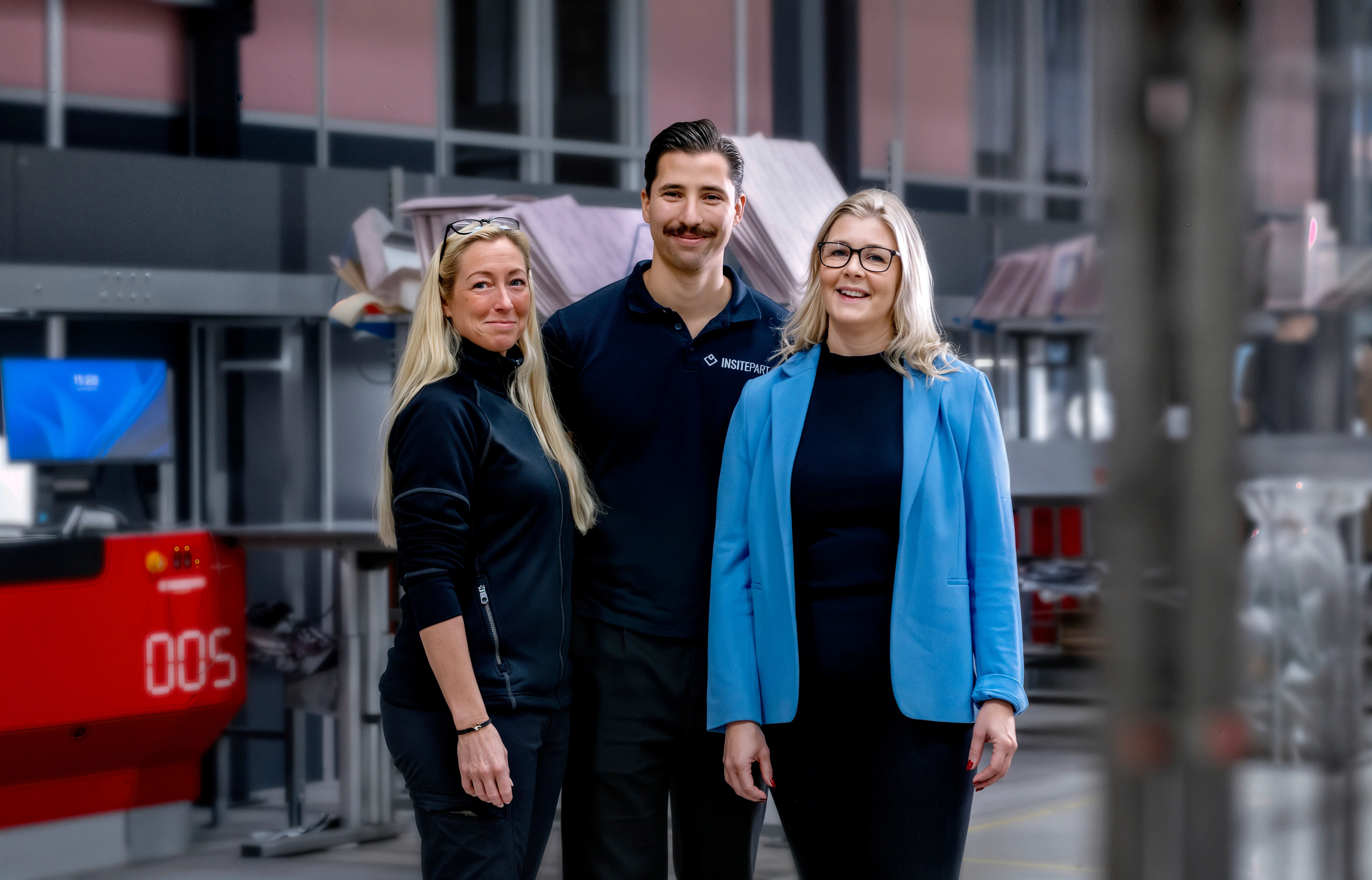 Tre anställda står tillsammans och ler mot kameran. En kvinna med blond hår, en man och en kvinna med glasögon.