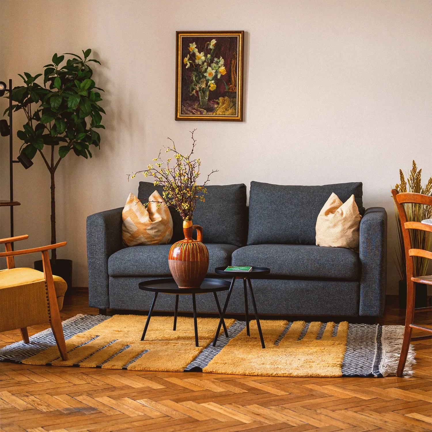 Boutique N°4 • living room with a grey sofa, round side tables, a yellow rug and a large plant