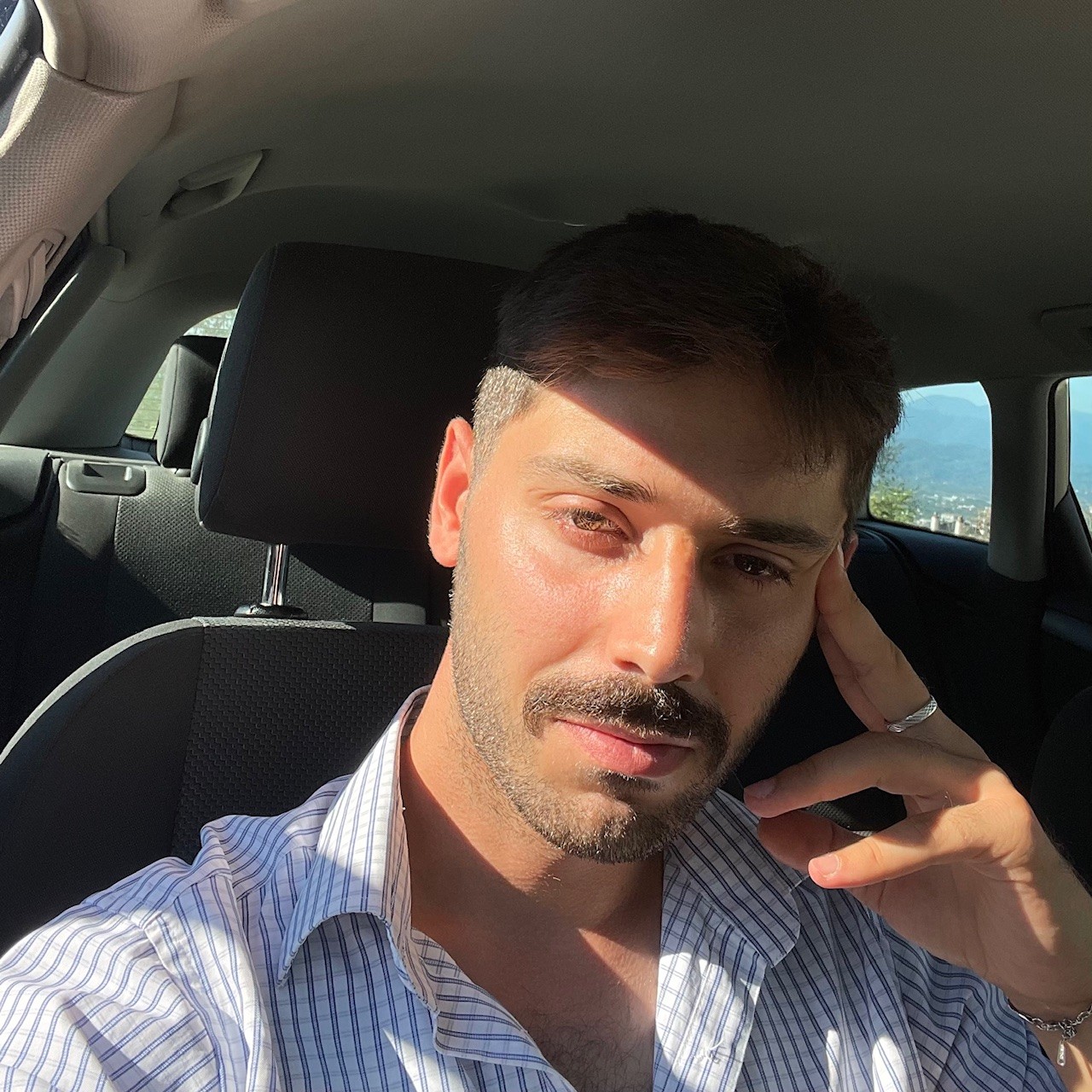 Smiling blonde woman with freckles in a white shirt, arms crossed, minimalist studio portrait.