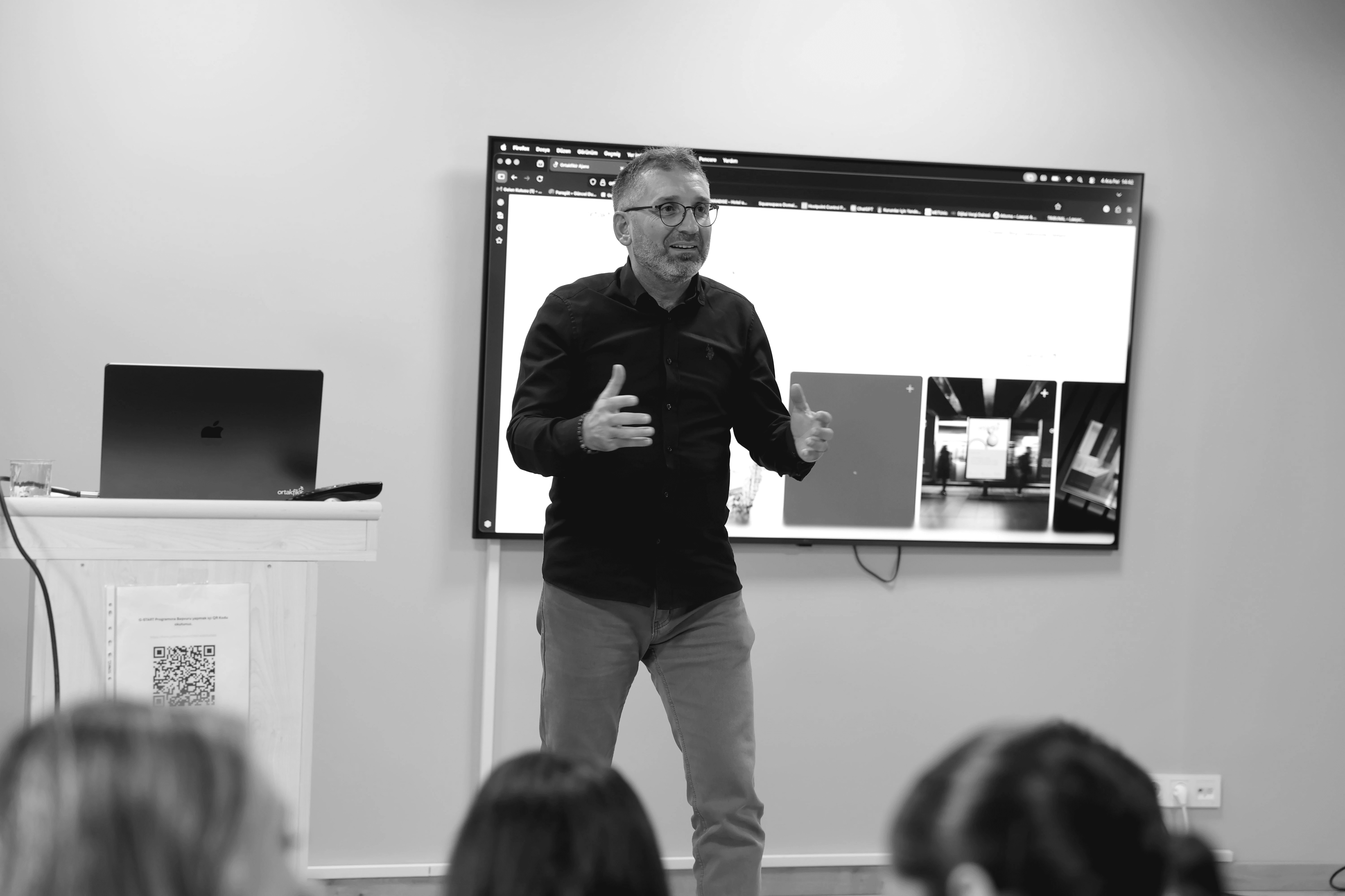Four people engage in conversation in front of a wall with text, all smiling and interacting in a casual setting.