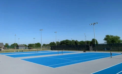 Renovated blue tennis courts at a country club facility with fresh surfacing and line striping.
