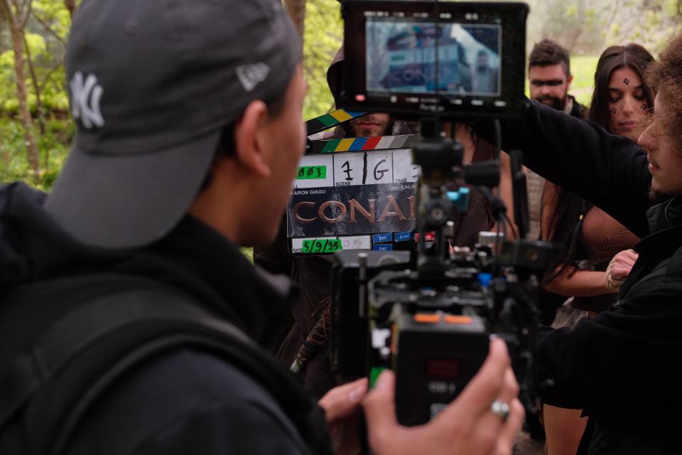 Silhouette of a camera operator filming on a professional set, surrounded by bright studio lights. The scene conveys focus and creative energy.