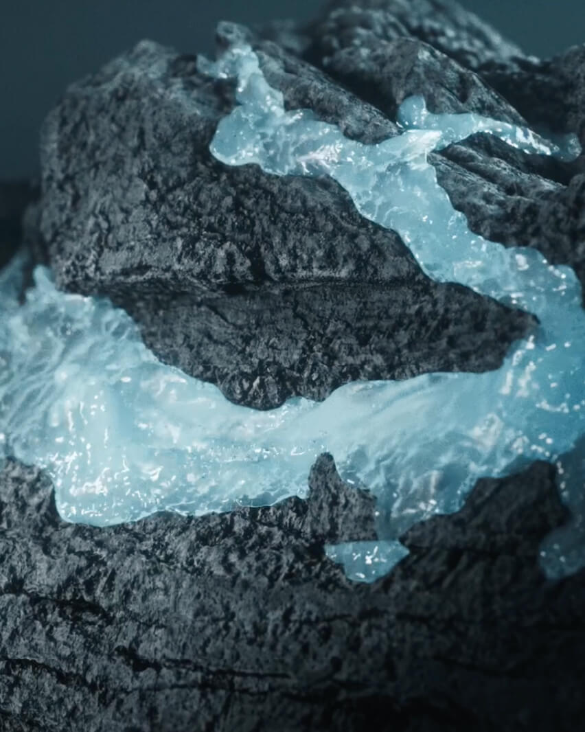 Two people stand together on a black-sand beach beneath bright green northern lights over the ocean. Photo: Icelandia