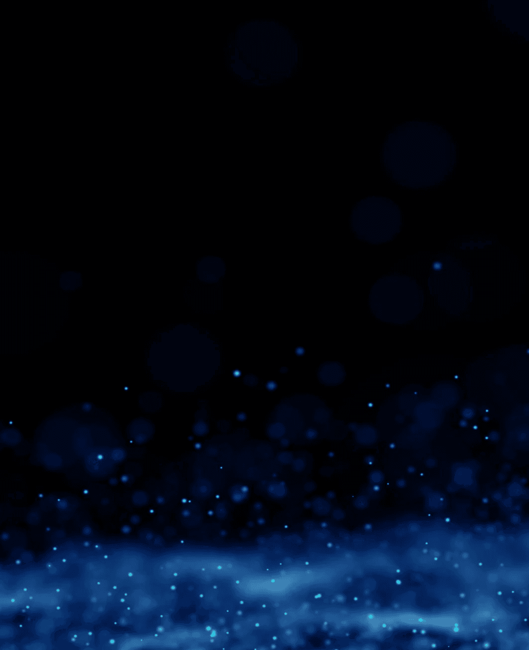 Close-up portrait of a person wearing a gray insulated hooded jacket with the hood up, showing their face framed by the hood against a light background.