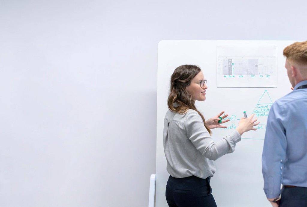Two people brainstorming with sticky notes on wall.