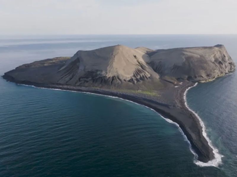 The volcanic island of Surtsey sits in the ocean as an isolated basalt volcano, off the coast of Iceland, with dramatic palagonite cliffs and new plant formation.
