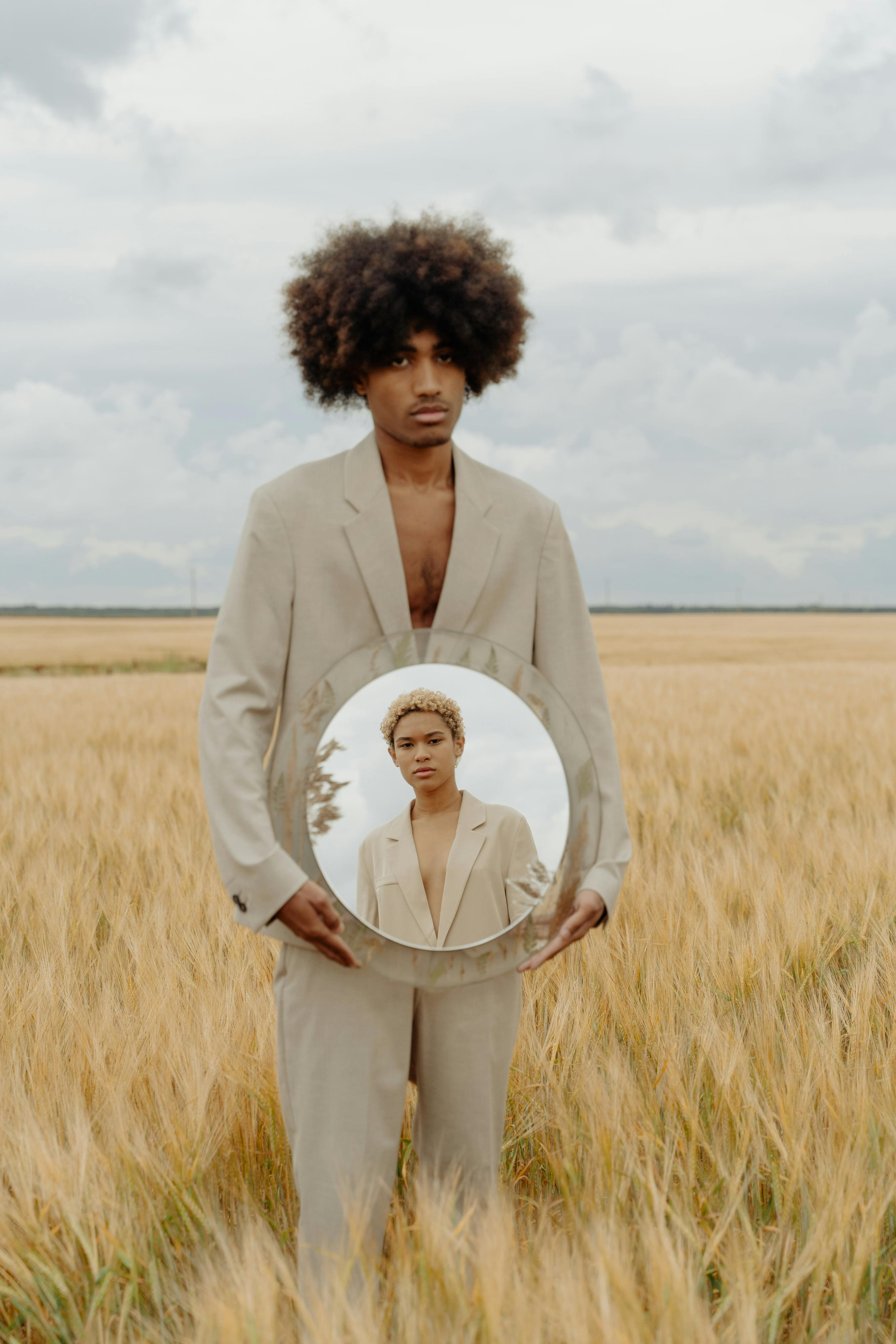 Man holding a mirror in a field.