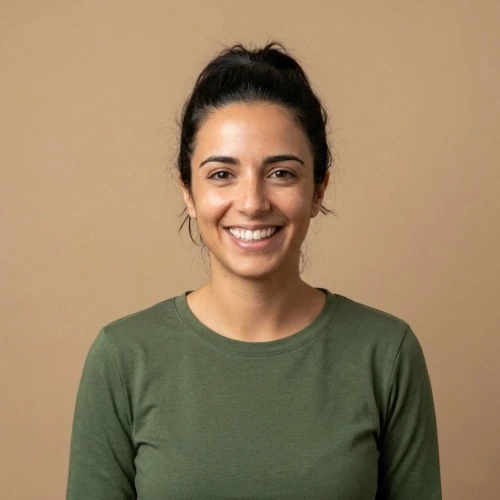 דיוקן פרונטלי של אביבית לוי, מנהלת שיווק ב"אופוס נדל"ן". אישה ישראלית צעירה עם חיוך רחב ושיער כהה אסוף, לבושה בחולצה ירוקה על רקע חום בהיר נקי. תמונת המלצה לאתר עלונים.