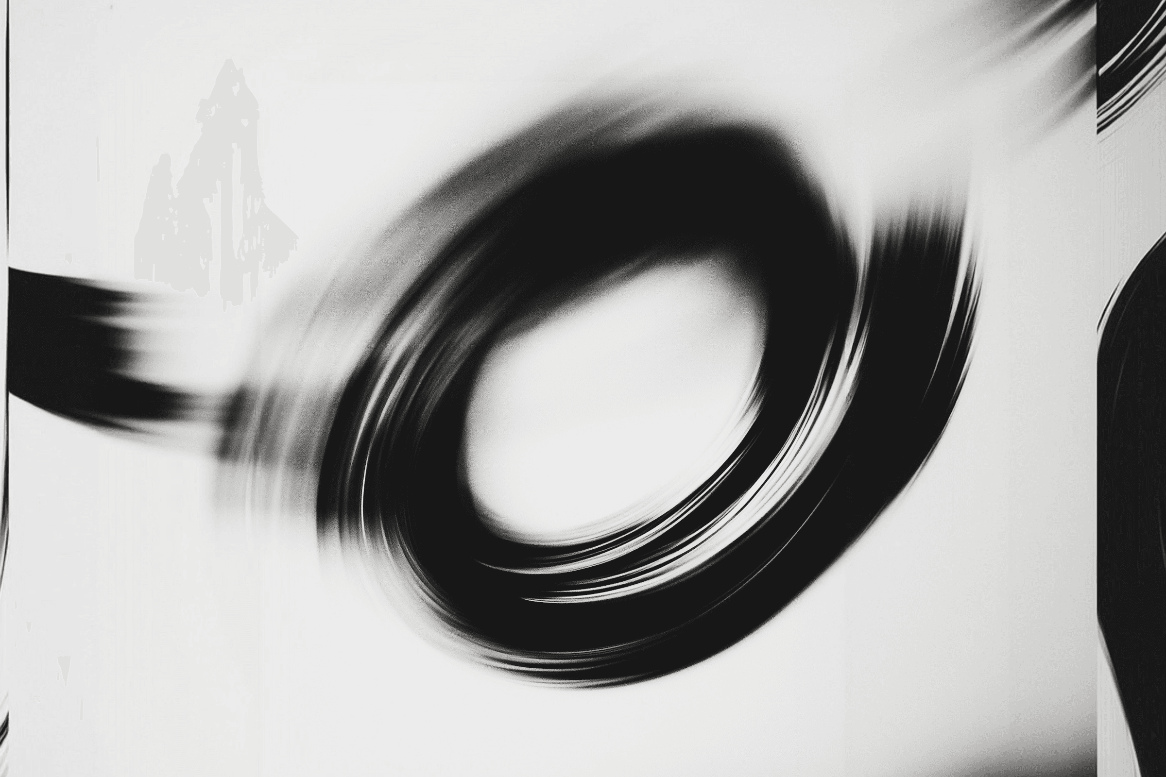 Abstract black circular brushstroke on white background, dynamic and blurred for a minimalist, modern aesthetic.