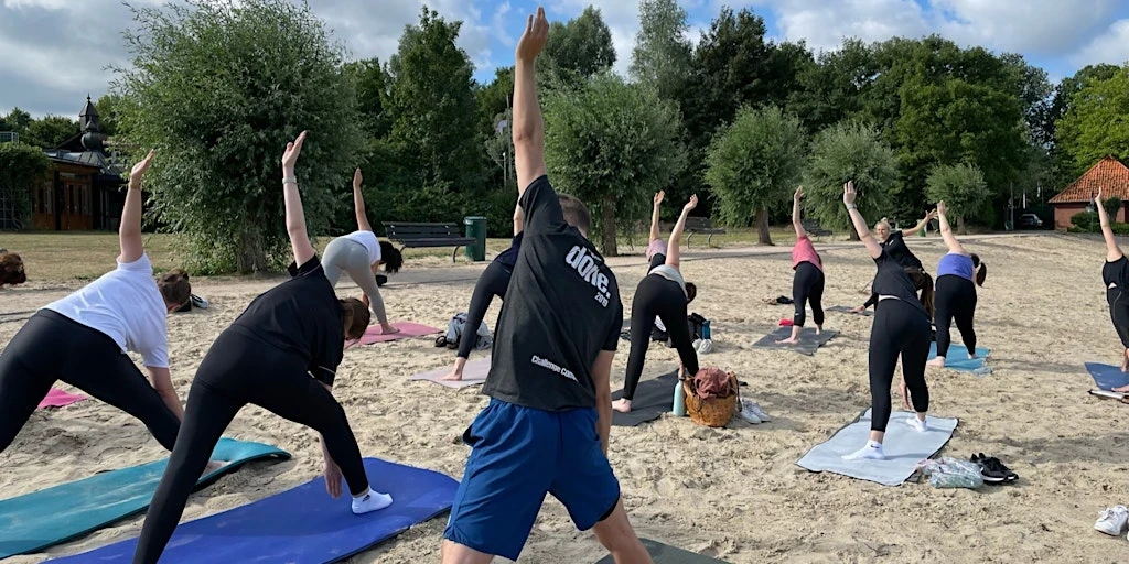 Teilnehmer machen Yoga am Dranländersee, genießen ein Picknick in der Natur – veranstaltet von Strong Partners, Experten für Betriebliches Gesundheitsmanagement.