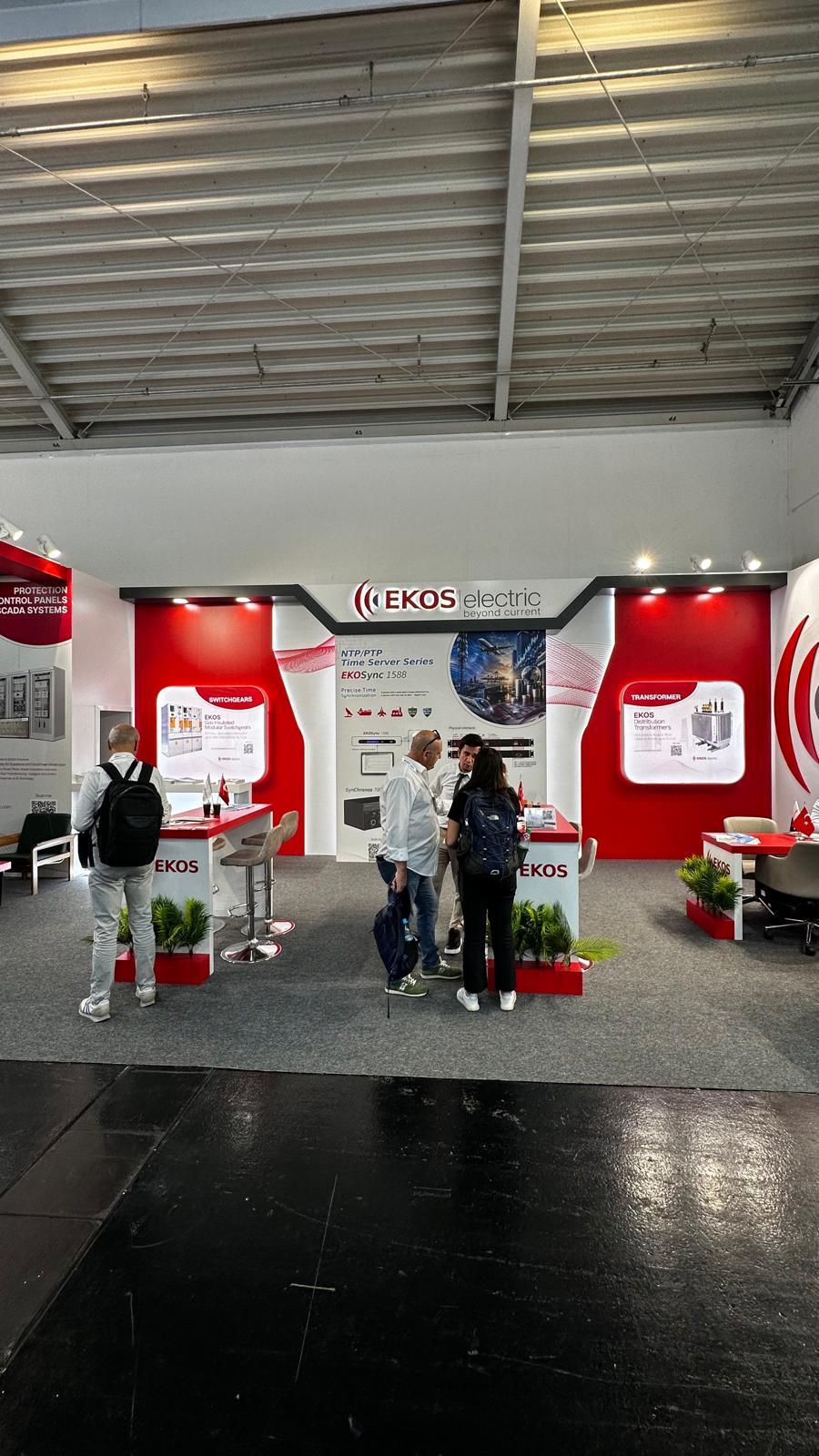 EKOS Electric exhibition stand at Intersolar 2026 Munich, featuring a curved wave‑like design inspired by the EKOS logo with red, white, and grey branding.