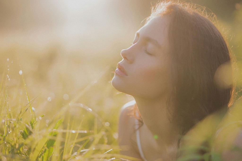 A person lying on a massage table, their face covered with a towel, bathed in warm golden light. The setting exudes relaxation and comfort.