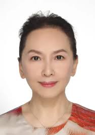 Woman with dark hair, smiling, against white background.
