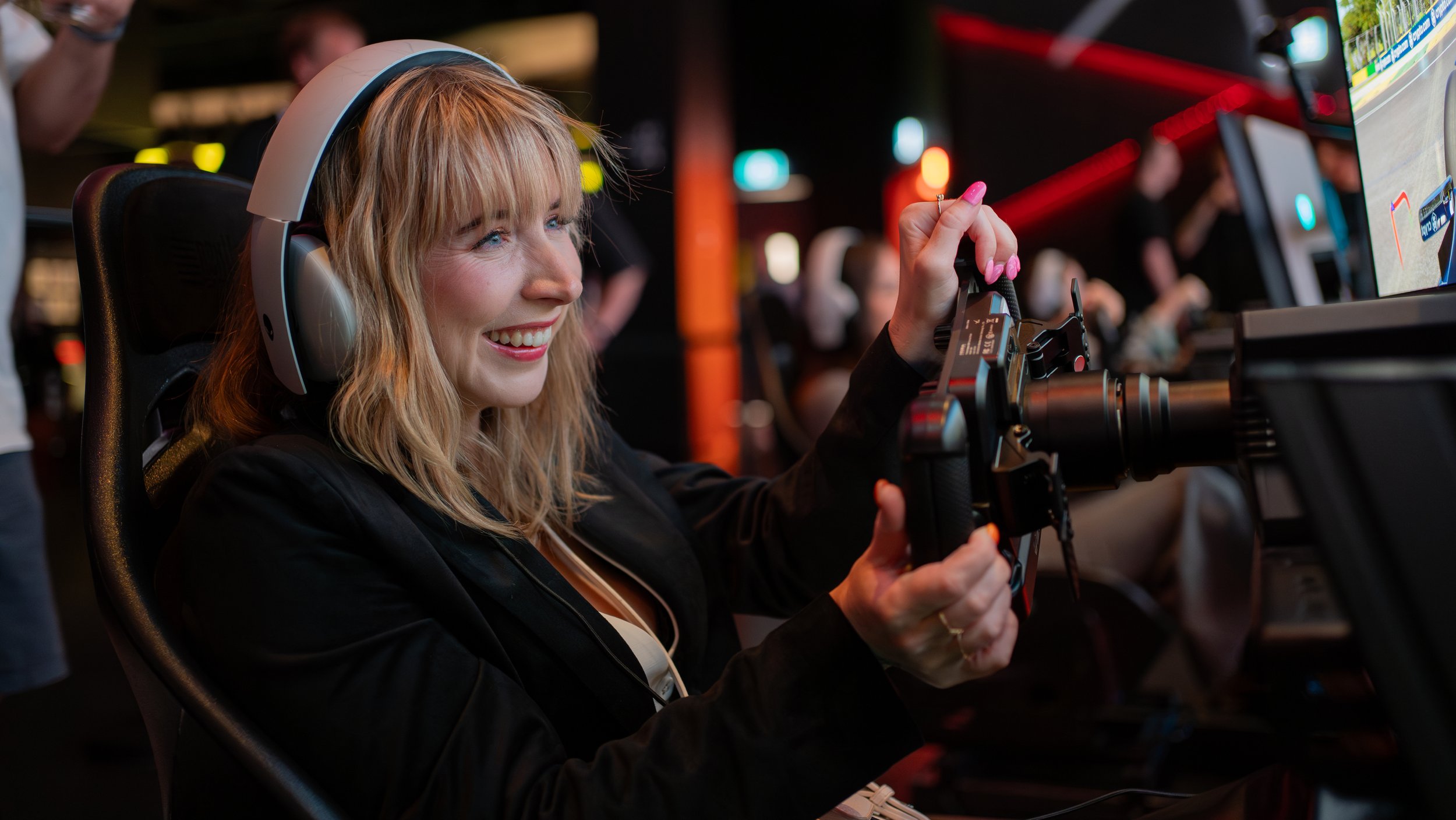 Someone wearing headphones playing on a driving simulation rig in the Arena at Fortress