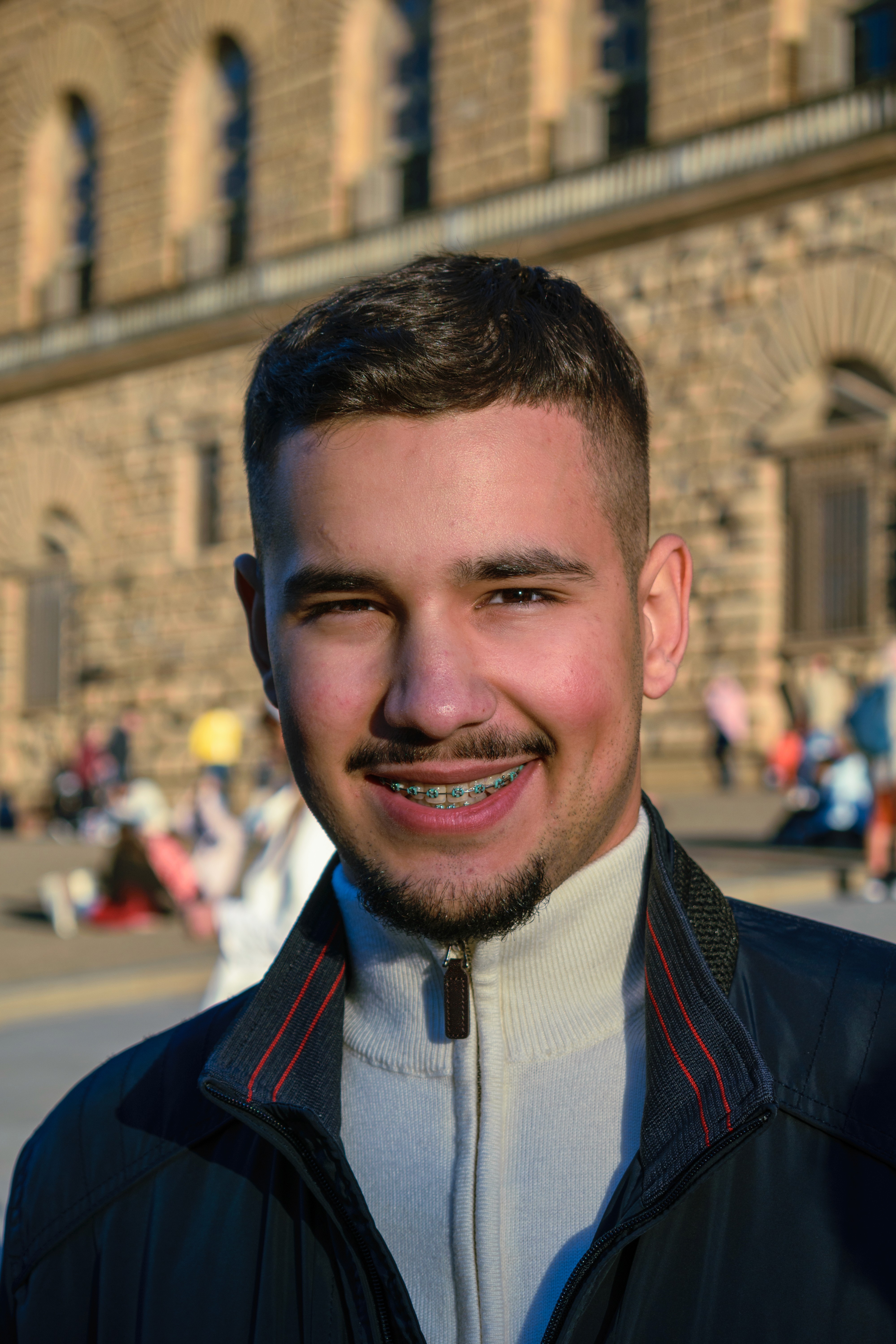 A person wearing sunglasses and a white zip-up sweater stands amidst a crowd in a bustling urban setting, with old brick buildings and storefronts in the background.

AI Developer Viktor Jovanovic, Founder of Profit Raiser Agency