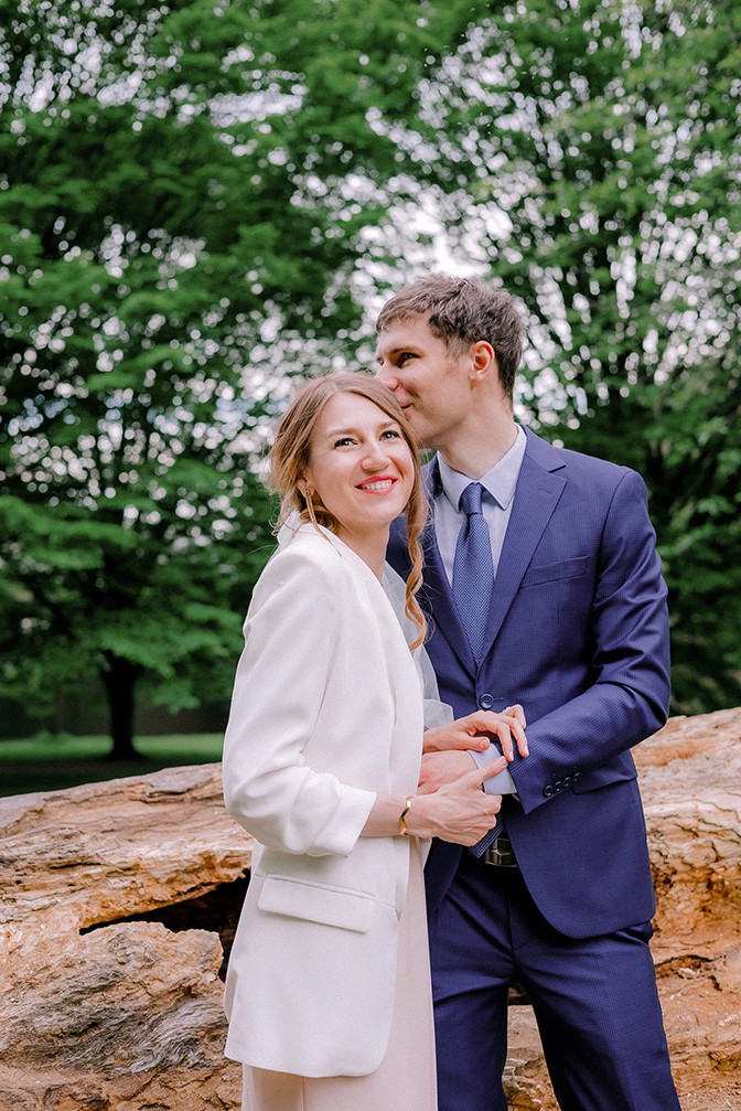 Outdoor wedding portrait of a couple smiling together in a park surrounded by green trees and natural light