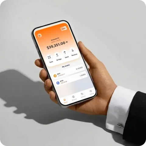 Hand holding iPhone displaying Bridgebu crypto wallet app with $39,351 balance showing BTC and ETH assets